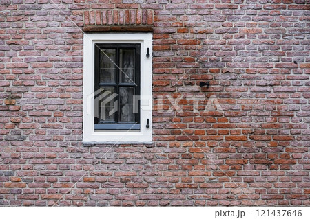 Facade view of window with curtain on brick wall background 121437646