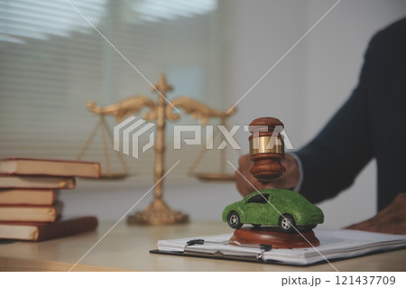 Judge gavel and miniature car symbolize auction or court case against driver who has accident and receiving vehicle insurance payment be on table in front of hands of lawyers. Selective focus 121437709