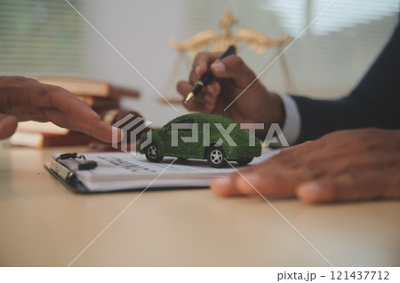 Judge gavel and miniature car symbolize auction or court case against driver who has accident and receiving vehicle insurance payment be on table in front of hands of lawyers. Selective focus 121437712