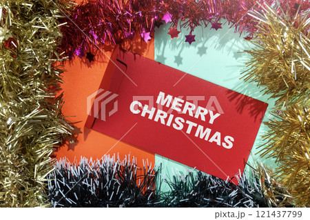 Closeup view of Merry Christmas text on an envelope with a Christmas ornament frame on a colored background 121437799