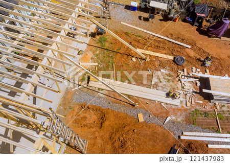 Workers are engaged in building framework structure with wooden beams while tools, materials are scattered around on construction work area Workers are engaged in building framework structure with wooden beams while tools, materials are scattered around on construction work area 121437983