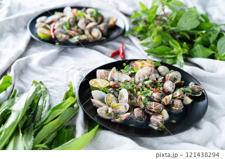 Plates of clams and mussels with garlic and vibrant green herbs ready for a seafood feast. 121438294