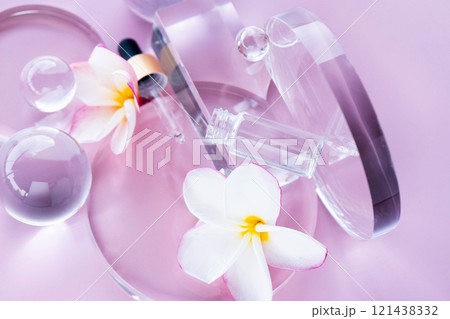 Display includes serum with aloe and centella, surrounded by glass elements and flower petals. Flat lay. Display includes serum with aloe and centella, surrounded by glass elements and flower petals. Flat lay. 121438332