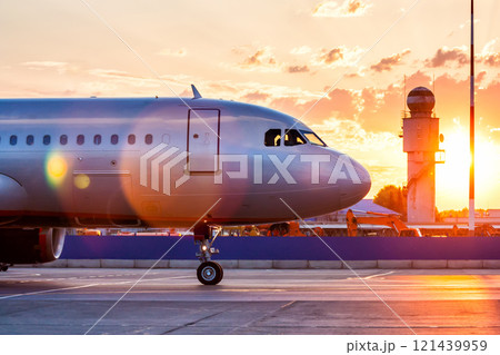 Close-up of the front of a passenger airplane. Aircraft taxiing on the apron of the airport in the rays of a picturesque sunrise 121439959