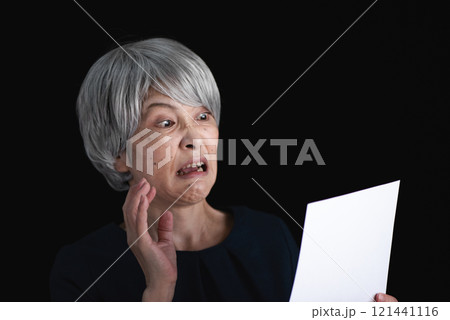 書類を見て驚くグレーヘアの女性 121441116