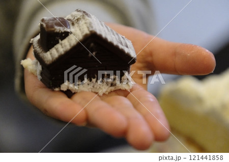 チョコレートでできた家のお菓子を手にのせる幼児 チョコレートでできた家のお菓子を手にのせる幼児 121441858