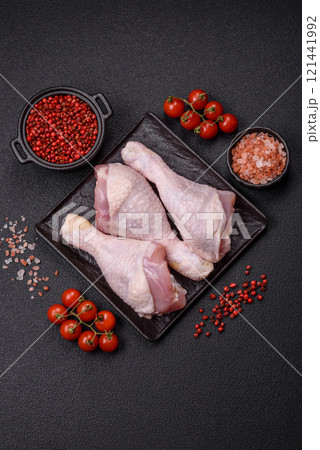Raw chicken legs with salt, spices and herbs on a dark concrete background Raw chicken legs with salt, spices and herbs on a dark concrete background 121441992