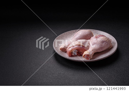 Raw chicken legs with salt, spices and herbs on a dark concrete background 121441993