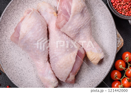 Raw chicken legs with salt, spices and herbs on a dark concrete background Raw chicken legs with salt, spices and herbs on a dark concrete background 121442000