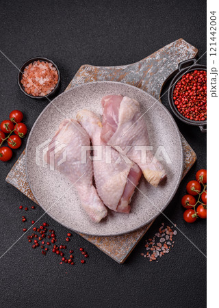 Raw chicken legs with salt, spices and herbs on a dark concrete background 121442004