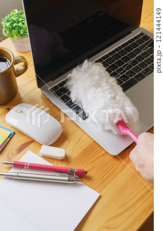 デスク上のノートパソコンをハンディモップで掃除する 121444149