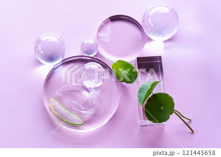 Aloe leaves and centella are displayed with serum droplets on a soft pastel backdrop. Aloe leaves and centella are displayed with serum droplets on a soft pastel backdrop. 121445658