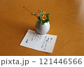 旅館の女将さんからの手紙とオレンジ色の花が添えられた小さな花瓶 121446566