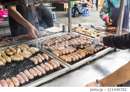 Close-up of the vendors grilling Taiwanese sausage and sticky rice (glutinous rice) sausage in the night market in Taiwan. This is one of the street snacks popular among tourists in Taiwan. Close-up of the vendors grilling Taiwanese sausage and sticky rice (glutinous rice) sausage in the night market in Taiwan. This is one of the street snacks popular among tourists in Taiwan. 121446782