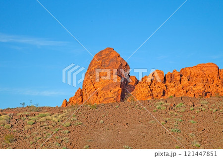Red rock desert landscape with dramatic rock formations and vibrant blue sky at golden hour 121447851
