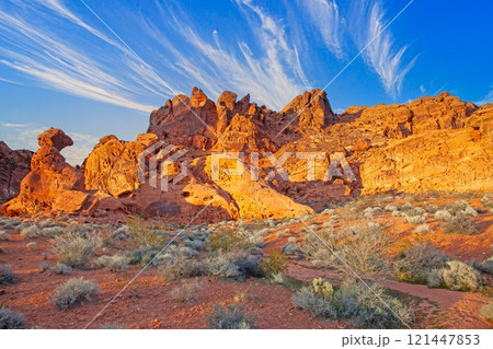 Red rock desert landscape with dramatic rock formations and vibrant blue sky at golden hour 121447853