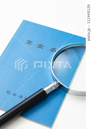 白背景に年金手帳と虫眼鏡 121448126
