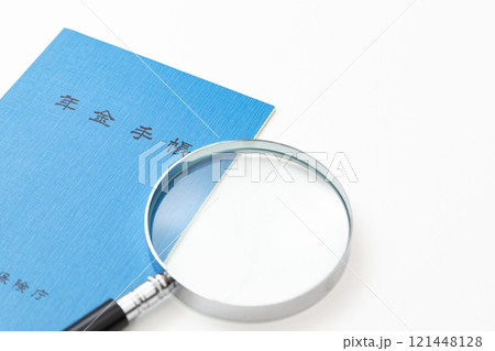 白背景に年金手帳と虫眼鏡 白背景に年金手帳と虫眼鏡 121448128