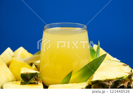 Pineapple juice in a glass among fresh pineapple fruit close-up. 121448526