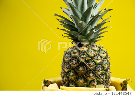 Whole pineapple and cut into pieces on a yellow background close-up. Whole pineapple and cut into pieces on a yellow background close-up. 121448547