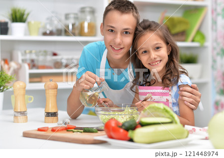 Cute little brother and sister preparing salad together at kitchen Cute little brother and sister preparing salad together at kitchen 121448974