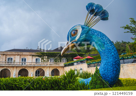 Sculpture of a giant peacock head in the garden 121449159