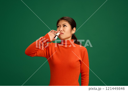 Woman applying nasal spray to combat congestion, common symptom of cold or flu viruses. Focus on respiratory relief and healthcare practices. 121449846