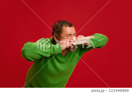 Man sneezing into tissue, face strained, highlighting flu virus spread, respiratory infection, and need for hygiene. Man sneezing into tissue, face strained, highlighting flu virus spread, respiratory infection, and need for hygiene. 121449869