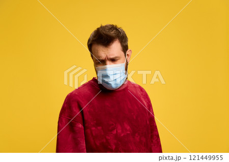 Young, sad, sick man with protective medical mask against yellow studio background. Respiratory viruses. Young, sad, sick man with protective medical mask against yellow studio background. Respiratory viruses. 121449955