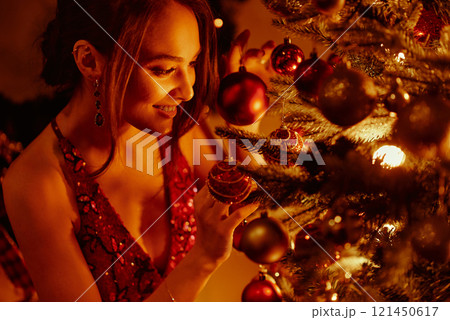 Smiling woman decorating festive Christmas tree. 121450617