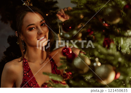 Smiling woman decorating festive Christmas tree. Smiling woman decorating festive Christmas tree. 121450635