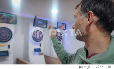 A man aims a dart at a darts machine. Concept of determination, gambling addiction. A man aims a dart at a darts machine. Concept of determination, gambling addiction. 121450916