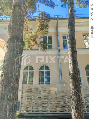A detailed view of a historic structure featuring elegant windows and a contemporary patterned fence. This photo showcases the coexistence of tradition and modernity in urban design. 121451813