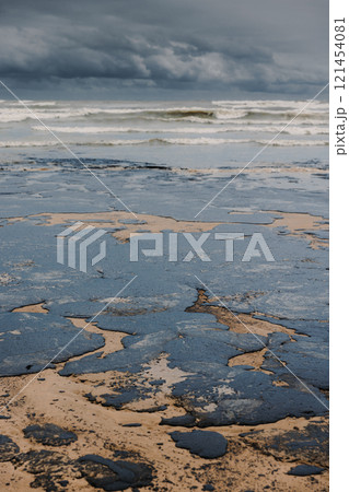 Oil leaked in coastline after a tanker wreck. Fuel oil polluted and destroying sandy beach Oil leaked in coastline after a tanker wreck. Fuel oil polluted and destroying sandy beach 121454081