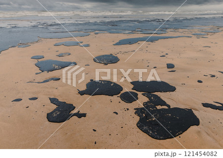 Oil leak in coastline after a tanker wreck. Fuel oil polluted and destroying beach 121454082