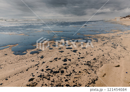 Oil leak in coastline after a tanker wreck. Fuel oil polluted beach Oil leak in coastline after a tanker wreck. Fuel oil polluted beach 121454084