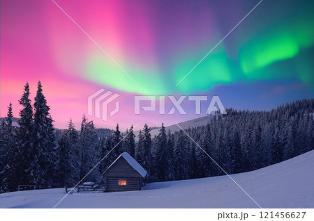 Small wooden cabin in snowy mountains under incredible Northern lights 121456627
