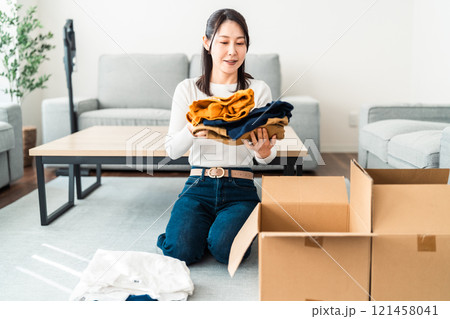 衣類を箱詰めする若い女性 衣類を箱詰めする若い女性 121458041