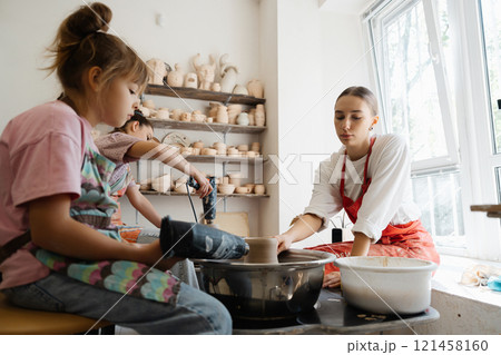 Children learning pottery skills in a bright workshop during the daytime Children learning pottery skills in a bright workshop during the daytime 121458160