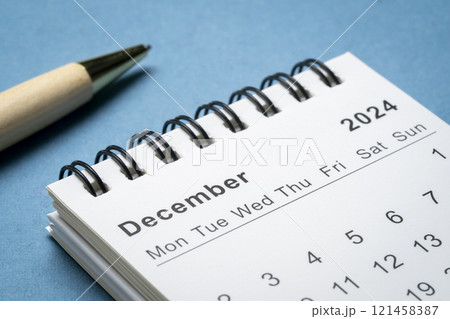 December 2024 - small spiral desktop calendar against abstract paper landscape, time and business concept 121458387