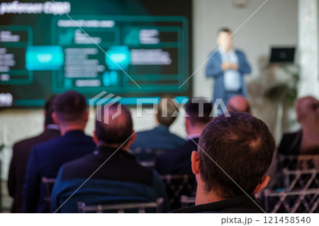 Business conference with people listening to speaker and presentation on screen 121458540