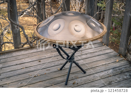 handpan drum on a stand outdoors, a modern, melodic percussion instrument made of steel, known for its soothing, resonant tones 121458728