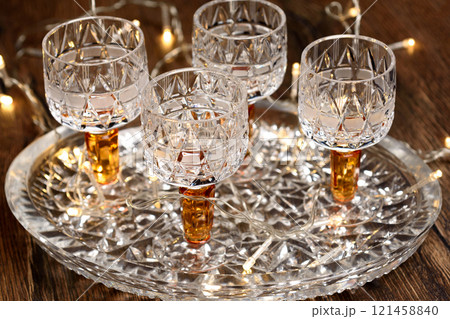 Close up of crystal wine glasses on crystal tray and Christmas garland. Close up of crystal wine glasses on crystal tray and Christmas garland. 121458840