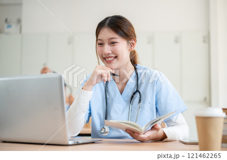 A smart Asian female medical student is focused on reading medical cases on her laptop. A smart Asian female medical student is focused on reading medical cases on her laptop. 121462265