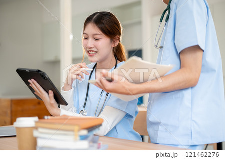 A beautiful Asian female medical is discussing work with her classmate in a library. A beautiful Asian female medical is discussing work with her classmate in a library. 121462276