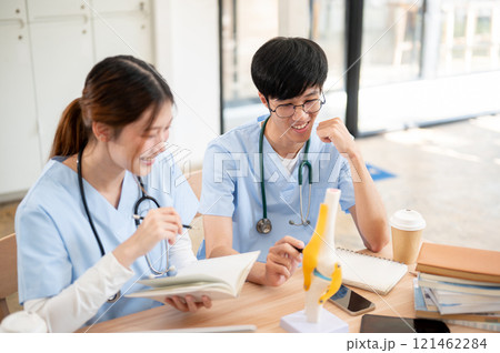 A female medical student is examining a model of bone joints and discussing it with her classmate. A female medical student is examining a model of bone joints and discussing it with her classmate. 121462284