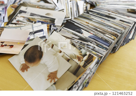 テーブルの上に重ねてて置かれたたくさんの写真プリント 121463252