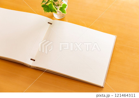 テーブルの上に開かれたアルバムの白い台紙のページ テーブルの上に開かれたアルバムの白い台紙のページ 121464311