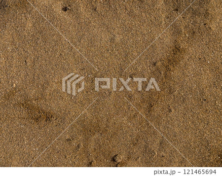 Golden brown sandy beach surface with small pebbles and subtle patterns 121465694