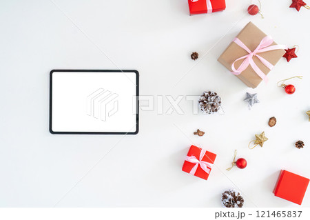 Tablet surrounded by Christmas gifts and decorations on a white background. Tablet surrounded by Christmas gifts and decorations on a white background. 121465837